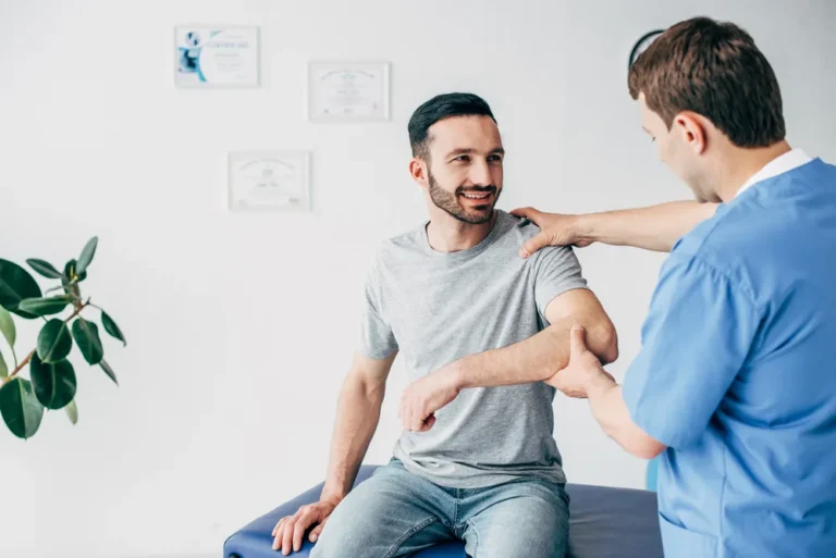 Chiropractor checking a patient’s shoulder movement during a shoulder injury exam in Canton, OH