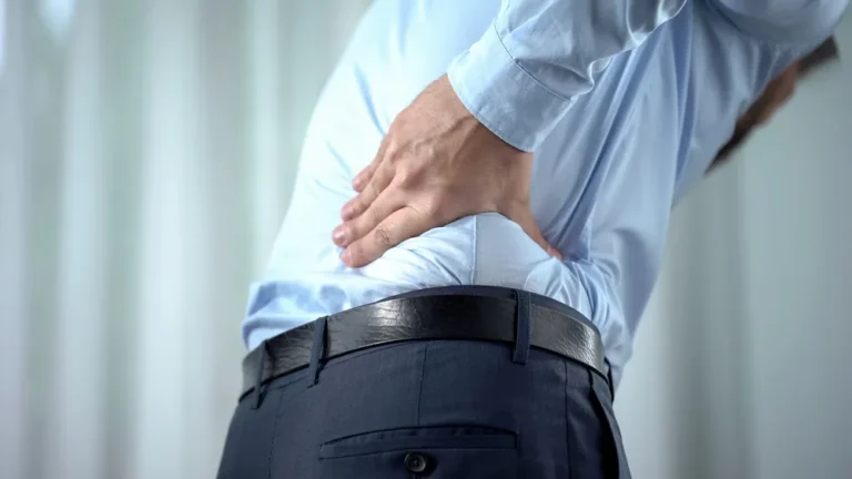 Man holding his lower back in pain from a spinal disc injury, seeking care in Canton, OH